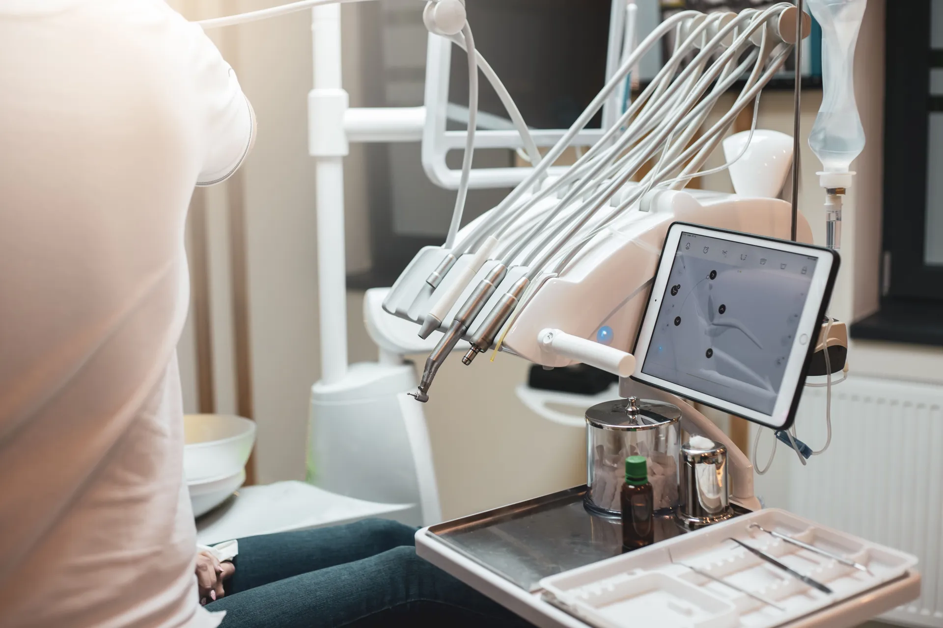 Consulta dental con equipo moderno y paciente en silla. Se observa un monitor y herramientas odontológicas en el consultorio.